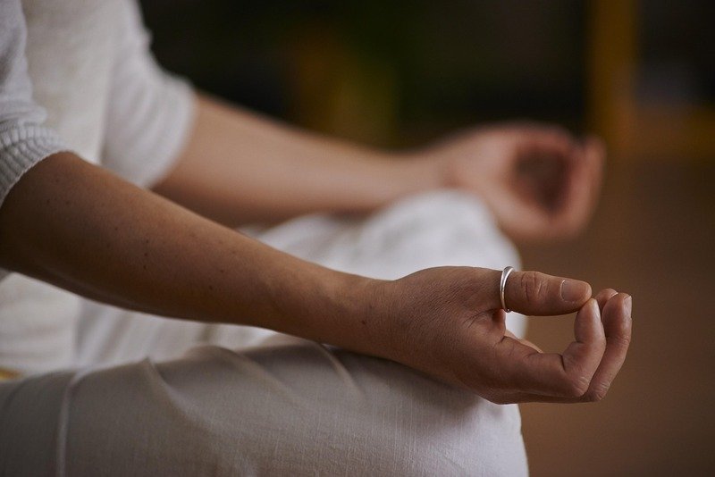 Gros plan sur les mains d'une personne en posture de méditation, les doigts formant un mudra, symbolisant le calme et la concentration.